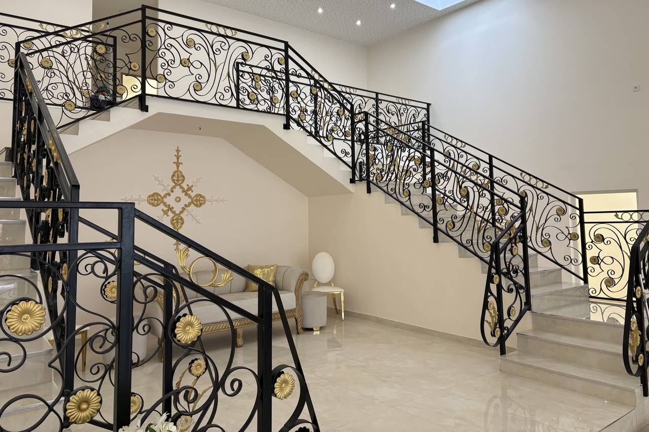 Escalier en fer forgé doré et noir dans le hall d'une salle de réception