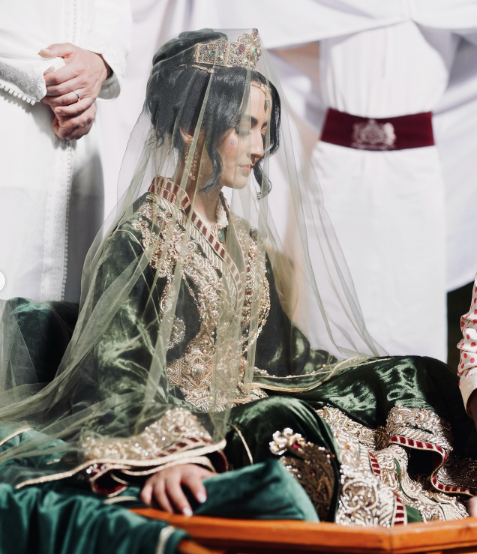 Mariée en tenue traditionnelle verte et dorée assise pendant une réception