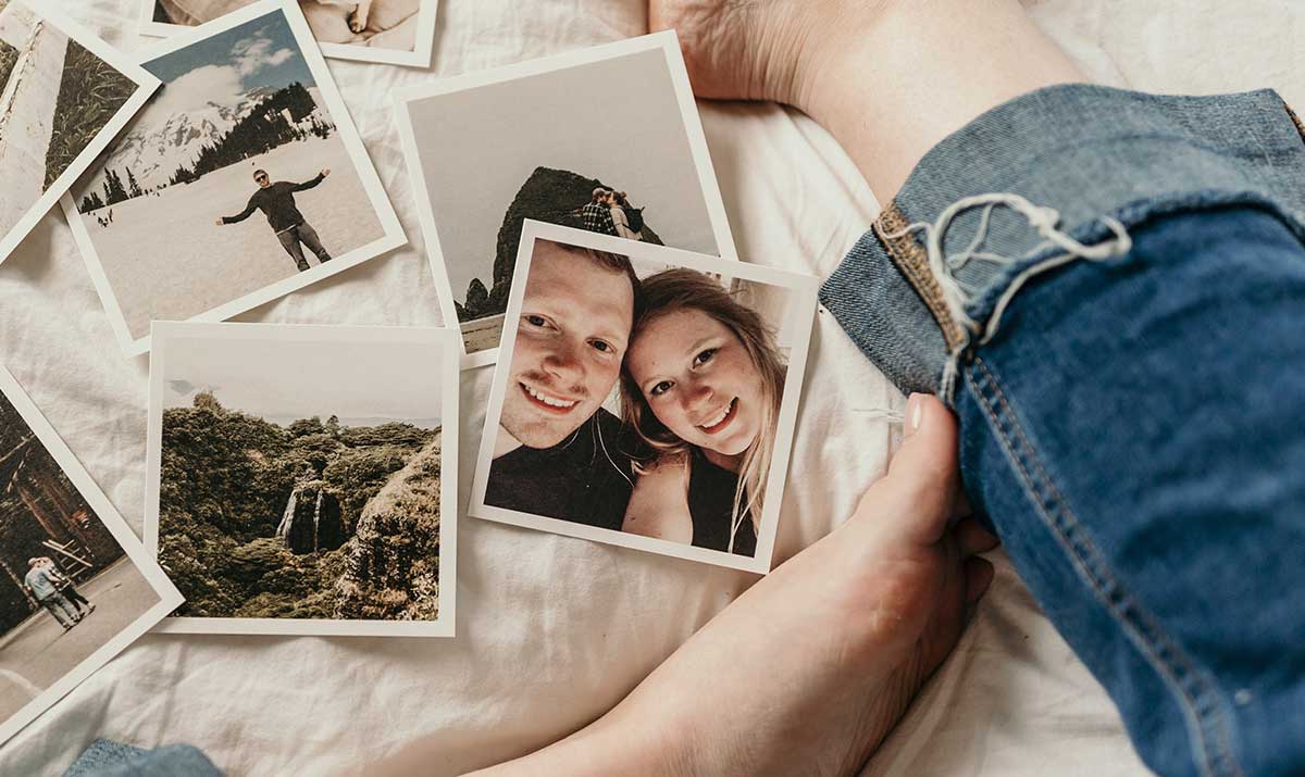 Photographies imprimées d'un couple et de voyages étalées sur un lit