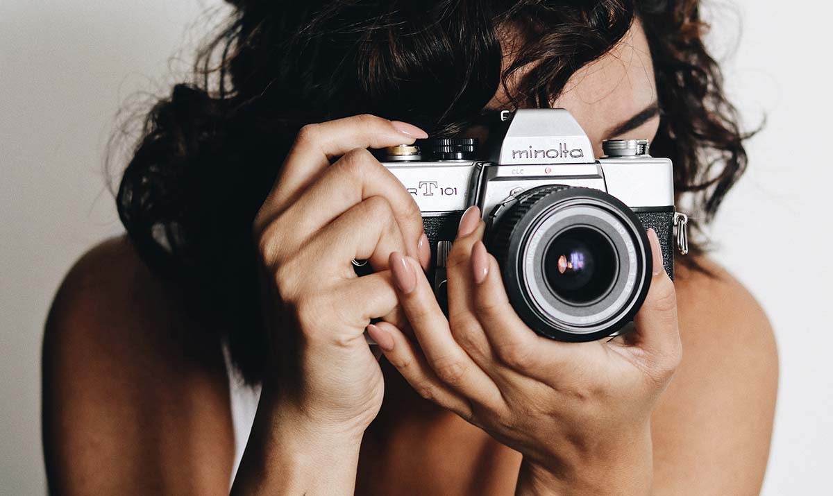 Photographe tenant un appareil photo argentique de type Minolta