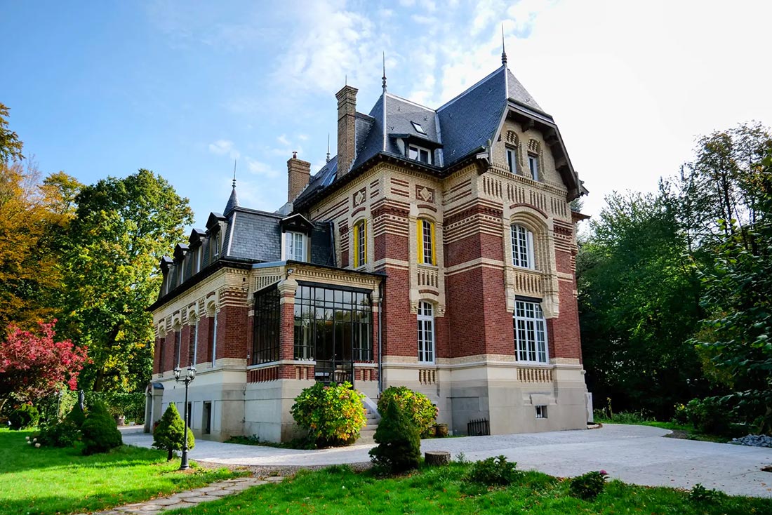 Façade en briques d'un château entouré d'un parc arboré dans l'Oise